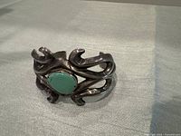 Front view of open cuff bracelet showing turquoise centerpiece and swirling silver design