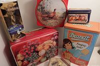 Seven vintage decorative tins arranged to display various designs and sizes.