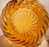 Close-up view of the bottom of amber glass bowl showing the raised swirl pattern and textured base.