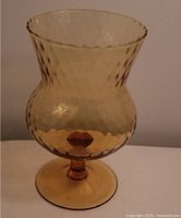 Front view of amber glass vase showing textured pattern and scalloped rim