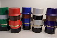 Side view of 5 Nutcracker candy tins in green, red, blue, white, and purple hats showing paint and design details.