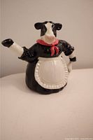 Front side view of the cow-shaped ceramic teapot showing colors and design of the main body and spout.