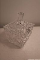 Close-up angled view of the crystal candy or sugar bowl showing the detailed cut glass pattern and lid finial.