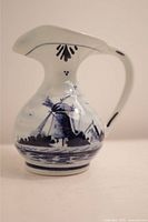 Front and side view of the small porcelain Delft vase featuring blue hand-painted windmill design and flared spout with curved handle.