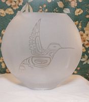 Front view of round frosted glass vase with etched hummingbird design.