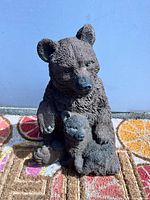 Front view of resin mama bear holding baby bear, detailed textured fur visible, on patterned surface.