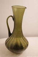Front view of green glass bud vase showing flared top, bulbous bottom, and handle.