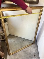 Photo showing the large gold frame being measured with a tape measure indicating approximately 38 inches width.