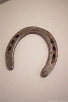 Light colored vintage horseshoe showing wear and rust spots on a white background
