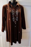 Front view of brown velvet top on mannequin, showing embroidered floral and leaf beading on front, long sleeves, collar, and button placket.