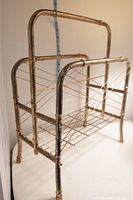 Side view of vintage brass magazine rack showing tubular brass structure and wire supports