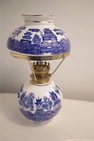 Full view of vintage ceramic lantern showing blue landscape design with pagodas and trees, brass fittings, and glass chimney.