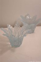 Front view of two blue petal-shaped vintage Murano glass tea light holders on a flat surface