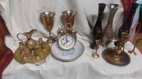 Group shot of all brass items including clock, tray set, goblets, vases, candleholders