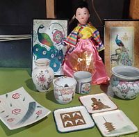 Group shot of entire lot showing framed prints, doll, porcelain items, plate and coasters