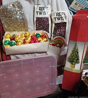 Assorted ornaments, garlands, storage tote and tree box grouped together