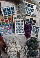 Overall lot with boxed blue and multi-colored ornaments, silver and purple garlands, two strings of lights