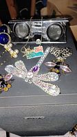 Lot overview showing dragonfly brooch, bee pins, hair pins, Expo pin, binoculars