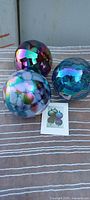 Three glass ornaments grouped on striped cloth with reference photo card