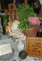 Group shot showing vases, plate, faux floral basket, plaques, glass ball and part of wooden shelf