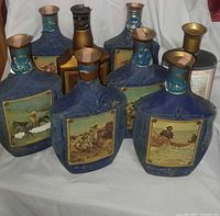 Group of eight blue Beam's Choice decanters with varied art panels, showing overall quantity and condition