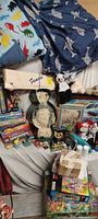Overview of assorted plush animals, PC games, model kit, puzzles and books on bed