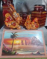 Group shot of three striped glass canisters, two ceramic roosters, and signed tile painting