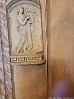 Close-up of Greek-style plaque with female figure playing a lyre showing carved details and textured background
