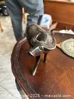 Photo of an antique bone carving of a water buffalo placed on a wooden table, showing detailed carving on the animal's body and face.