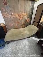 Full view of the chaise lounge showing green velvet upholstery and flowing curved shape