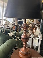 Side view of antique copper lamp with three arms and black lampshade, set in a room environment.