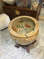 Full view of the ceramic plant holder on wooden stand showing exterior crane and gold leaf designs.