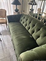 Left-side angle view showing tufted back, rolled arm and skirt detail