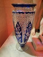 Full view of tall 13-inch hand cut crystal vase with blue accents and floral etching.
