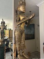 Full view of the statue showing standing goddess on lotus pedestal with hands in prayer position