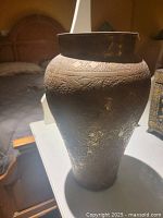 Photo of large carved brass vase showing detailed engravings and shape