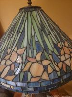 Close-up of stained glass shade showing floral mosaic pattern in green, blue, pink and cream glass pieces.