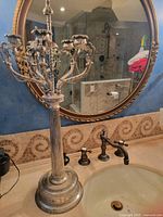 Full view of the large silver candelabra standing on a bathroom sink countertop with mirror in background.