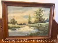 Framed oil painting of a rustic landscape with river and trees
