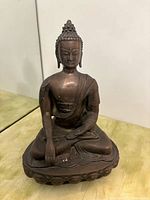 Frontal view of metal seated Buddha statue on lotus base
