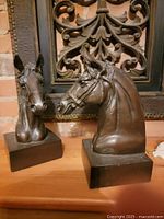 Close-up photo of the two bronze horse head bookends showing fine detail on the sculptures and solid square bases.