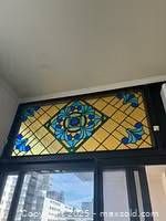 Full view of rectangular stained glass panel installed above a window