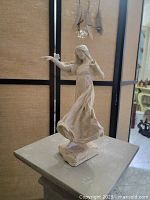 Photo of a 9-inch tall statue of a girl with an outstretched hand; a butterfly rests on her finger, showing intricate detail on dress and hair.