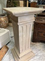 Side view of the stone column pedestal showing its fluted design and square base.