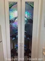 Photo of the two long stained glass panels installed in a double door frame. Panels show colorful water lily and water design with textured glass.