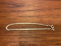 Full length view of box chain bracelet on wood surface