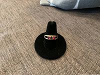 Front view of ring on black velvet display stand showing three-stone arrangement.