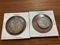 Two British silver coins in cardboard holders, front sides shown with year, denomination, and silver content handwritten on holders.