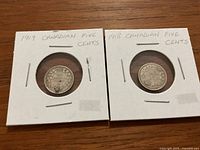 Top side view of 1919 and 1918 Canadian silver nickels enclosed in protective white cardboard holders with labeling.