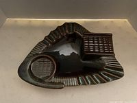 Top view of the ashtray showing the glossy dark ceramic surface with basket weave texture on one side and circular depression for ashes.